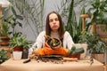 House florist with gloves. Botanist with houseplants. Female demonstrating flower care. Unhappy sad woman florist wearing apron Royalty Free Stock Photo