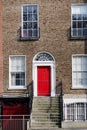House front with stairs red door, brick stone, and glass windows Royalty Free Stock Photo