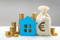 House and gold coins with bag and euro symbol. Concept for expensive real estate in the European Union Royalty Free Stock Photo