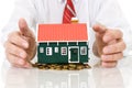 House on golden coins pile with businessman hands Royalty Free Stock Photo