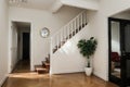 House hallway entrance interior with stairs and furniture. Apartment background with door, mirror, bag on hanger, flower in vase, Royalty Free Stock Photo