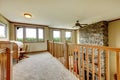 House hallway with stone fireplace and wood railing.