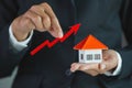 The house in the hands of a businessman and a red arrow, Up arrow and houses. Growth in real estate prices market. Buying and