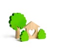 A house with a heart and wooden figures of trees with bushes on an isolated background. The concept of a love nest. Acquisition Royalty Free Stock Photo