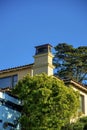 House hidden in the front or back yard trees with visible chimney vents metal with copy space blue sky background