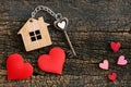 House key in heart shape with home keyring on old wood background decorated with mini heart