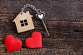 House key in heart shape with home keyring on old wood background decorated with mini heart