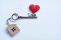 House key in heart shape with home keyring on white wood background decorated with mini heart Royalty Free Stock Photo