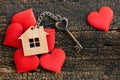 House key in heart shape with home keyring on wood background decorated with mini hearts