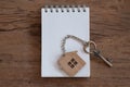 House key with home keyring, blank notebook and pencil on old wood table background Royalty Free Stock Photo