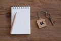 House key with home keyring, blank notebook and pencil on white wood table background Royalty Free Stock Photo