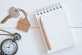 House key with home keyring, blank notebook and pencil on white wood table background Royalty Free Stock Photo