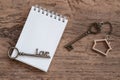 House key with home keyring, blank notebook and pencil on wood table background Royalty Free Stock Photo