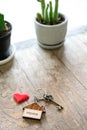 House key with home keyring decorated with mini heart on rusty wood background Royalty Free Stock Photo