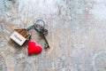 House key with home keyring decorated with mini heart on rusty wood background Royalty Free Stock Photo