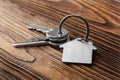 House key on house shaped keychain on wooden floorboards