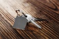 House key on house shaped keychain on wooden floorboards