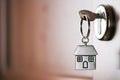 House key on a house shaped silver keyring in the lock of a entrance brown door Royalty Free Stock Photo