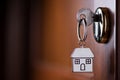 House key on a house shaped silver keyring in the lock of a entrance door