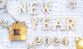 House key with keychain cottage on cozy festive knitted background with stars, bokeh. Happy New Year 2024 wooden letters, greeting