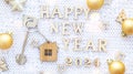 House key with keychain cottage on cozy festive knitted background with stars, bokeh. Happy New Year 2024 wooden letters, greeting