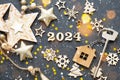 House key with keychain cottage on festive background with stars, lights of garlands. New Year 2024 wooden letters, greeting card
