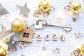 House key with keychain cottage on festive background with stars, lights of garlands. New Year 2024 wooden letters, greeting card