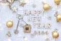 House key with keychain cottage on festive knitted background with stars, lights of garlands. Happy New Year 2024-wooden letters,