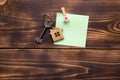 House key with a keychain in the shape of a cottage on a wooden background on sheet notes with Christmas decor. Dream fulfillment,