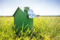 House key on a house shaped keychain with green wooden eco home on grass Royalty Free Stock Photo