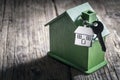 House key on a house shaped keychain with green wooden home environmentally friendly property Royalty Free Stock Photo