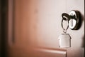 House key on a house shaped silver keyring in the lock of a entrance brown door Royalty Free Stock Photo