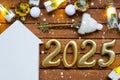 House key with tiny figure of home mock up on festive brown wooden background, lights of garlands. New Year 2025 wooden letters,