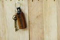 House key with wooden home keyring hanging on wood board background, property concept, copy space Royalty Free Stock Photo