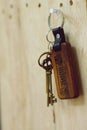 House key with wooden home keyring hanging on wood board background, property concept, copy space Royalty Free Stock Photo