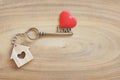 House keyring and love shape key on vintage wooden table. Decorated with mini heart as sweet gift for lover or family member. Home