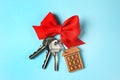 House keys with trinket and bow on color background