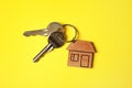 House keys with trinket on color background