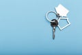 House keys with trinket on color background, top view with copy space. House key on blue background. Minimal flat lay style with