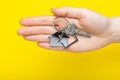 House keys with trinket in female hand on color background, top view with copy space. House key on yellow background. Minimal flat Royalty Free Stock Photo