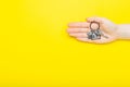 House keys with trinket in female hand on color background, top view with copy space. House key on yellow background. Minimal flat Royalty Free Stock Photo