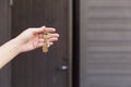 House keys in woman`s hand in front of the front door. Real esta