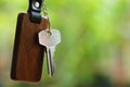 House keys with wooden home keyring with green garden background, property concept, copy space Royalty Free Stock Photo