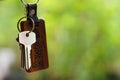 House keys with wooden home keyring with green garden background, property concept, copy space Royalty Free Stock Photo