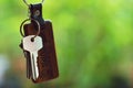 House keys with wooden home keyring with green garden background, property concept, copy space Royalty Free Stock Photo