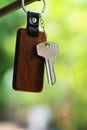 House keys with wooden home keyring with green garden background, property concept, copy space Royalty Free Stock Photo