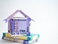 A house made with folded notes and bundles of money on white surface for finance concept Royalty Free Stock Photo