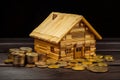 house made out of wooden sticks with money around it on a dark surface Royalty Free Stock Photo