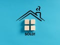 House made of wooden blocks on blue background with the word sold