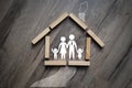 House made of wooden pieces with family stick figures on wooden background metaphor for dream of home ownership Royalty Free Stock Photo
